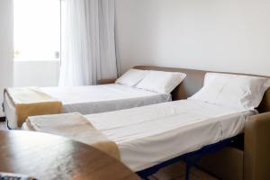 Duas camas num quarto com uma janela em Makkai Resort Bombinhas em Bombinhas