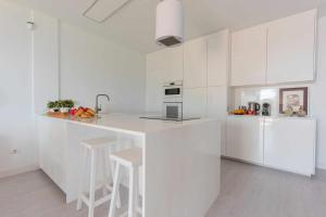 Una cocina blanca con encimera y taburetes. en Luxury Villa y Ocean View en Santa Cruz de Tenerife