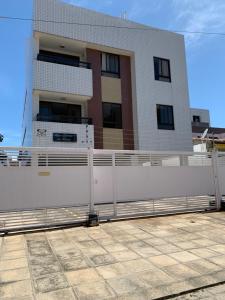 uma cerca branca em frente a um edifício em Praia e Sol Apto a 3 quadras do Bessa Beach. em João Pessoa