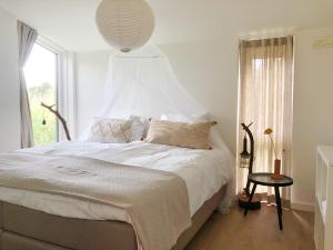 a bedroom with a large white bed with a window at Bungalow 82 op Recreatiepark De Wielen in Sint Maarten +38 photos