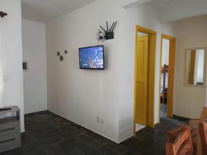 een woonkamer met een tv aan de muur bij CONDOMINIO COLONIAL APARTAMENTOS 150M DA PRAIA in Bombinhas