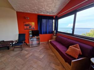 ein Wohnzimmer mit einem lila Sofa und großen Fenstern in der Unterkunft Casa di Poseidone in Brucoli