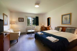 a bedroom with a large bed and chairs in it at Hotel Skanderborghus in Skanderborg