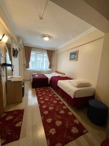 イスタンブールにあるアモーレ ホテル イスタンブールのベッド2台と赤い敷物が備わるホテルルームです。