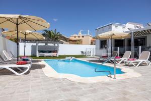 een zwembad met stoelen en parasols en een huis bij Ideal for family holidays, near beach and golf- Casa James in La Guirra