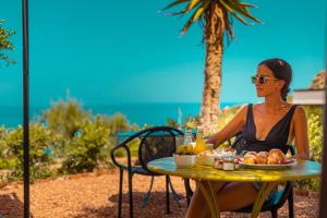 une femme assise à une table avec une assiette de fruits dans l'établissement Villa Totò Resort, à Cefalù