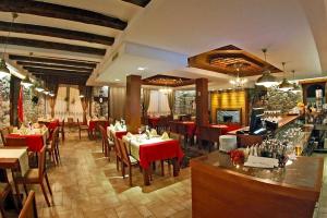a restaurant with red tables and chairs and a bar at Hotel - Kulla e Zenel Beut in Peje