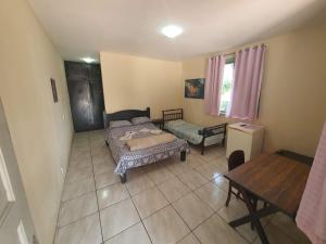 um quarto com uma cama, uma mesa e uma janela em Espaço La Gondola em Araruama