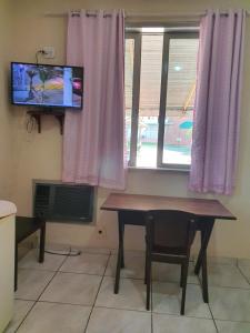 uma mesa e uma televisão num quarto com uma janela em Espaço La Gondola em Araruama