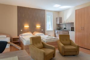 a hotel room with two beds and two chairs at BALATONAIR Vendégház in Balatonfüred