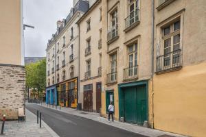 une personne marchant dans une rue à côté des bâtiments dans l'établissement LE SAINT LOUIS - Apt 3 chambres au cœur de Rennes, à Rennes