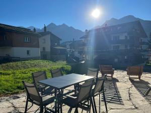 a table and chairs on a patio with the sun at Vieux Village in Grächen