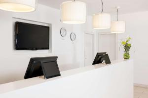 a waiting room with a flat screen tv and a mirror at NH Frankfurt Messe in Frankfurt/Main