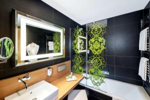ein Bad mit einem Waschbecken und einem Spiegel in der Unterkunft NH Frankfurt Messe in Frankfurt am Main