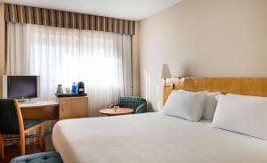 a hotel room with a bed and a desk and a television at NH Ciudad Real in Ciudad Real
