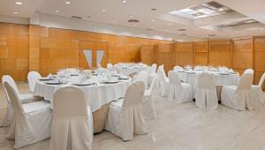 シウダー・レアルにあるNH シウダ レアルの白いテーブルと白い椅子が備わる宴会場