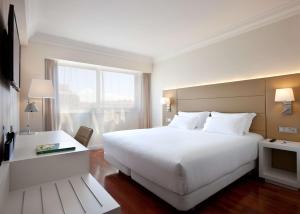una habitación de hotel con una gran cama blanca y una ventana en NH Pamplona Iruña Park, en Pamplona
