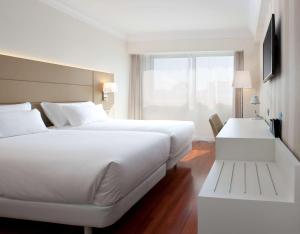 a hotel room with a large white bed and a window at NH Pamplona Iruña Park in Pamplona