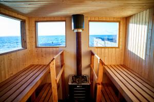 un sauna avec un poêle au milieu et trois fenêtres dans l'établissement Borghamn Strand, à Borghamn