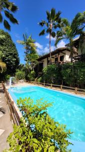 a blue swimming pool with palm trees and a house at Taipabas Hotel in Barra Grande