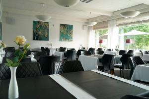 a dining room with tables and chairs and flowers at Hotel Skanderborghus in Skanderborg