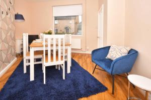 uma sala de jantar com uma mesa e uma cadeira azul em All Saints House by YourStays em Stoke on Trent