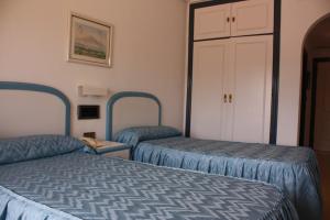 a hotel room with two beds and a closet at Hotel Playa Grande in Puerto de Mazarrón