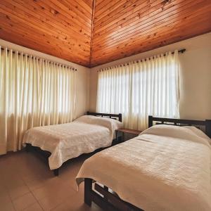 1 dormitorio con 2 camas y techo de madera en Hotel Campestre Tacurrumbi, en Montenegro