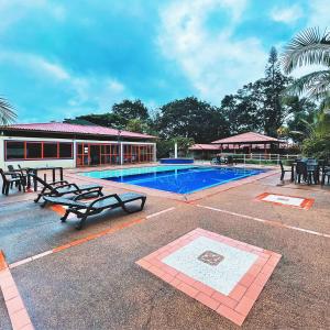 a swimming pool with benches and a building at Hotel Campestre Tacurrumbi in Montenegro