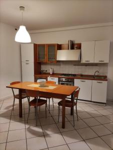 una cucina con tavolo in legno e alcune sedie di Appartamento La Fisarmonica Recanati a Recanati
