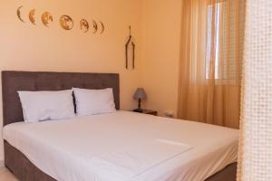 a bedroom with a bed with white sheets and a window at Sunday Apartments in Nafplio