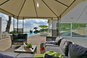 uma sala de estar com um sofá e um guarda-chuva grande em Villa Nausica pool view on the sea wifi free perfect for big group em Ragusa