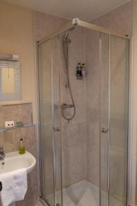 a shower with a glass door next to a sink at The Kings Head Hotel in Abergavenny