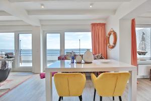 una sala da pranzo con tavolo bianco e sedie gialle di Strandallee 10 Penthouse Seaview a Haffkrug
