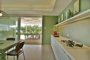 a kitchen with a stove and a dining room with a table at Villa Nausica pool view on the sea wifi free perfect for big group in Ragusa