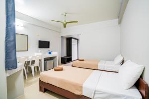 a hotel room with two beds and a table at Pasawang Hotel (โรงแรมภาสว่าง) in Hat Yai