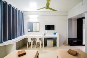 a living room with a table and chairs and a tv at Pasawang Hotel (โรงแรมภาสว่าง) in Hat Yai