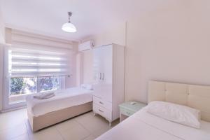 a white bedroom with two beds and a window at Apartments Near to City Center and Beach in Marmaris