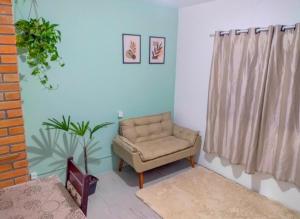 een woonkamer met een stoel en een plant bij Apartamento Suíte encantador in Gramado