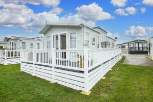a white house with a white fence in a yard at Luxury Caravan At Seaview Holiday Park In Kent Ref 47034pb in Whitstable