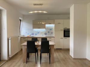 a kitchen with a wooden table and black chairs at Apartment Vrtacnik in Štefanja Gora