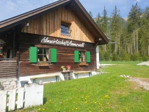 a log building with green windows and a sign on it at Ammerwald Alm in Plansee