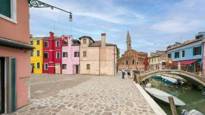 a group of buildings next to a canal with a bridge at Pink Paradise in Burano