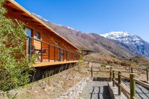 ein Holzhaus mit einem Balkon auf einem Berg in der Unterkunft Lodge El Morado in Refugio Lo Valdés