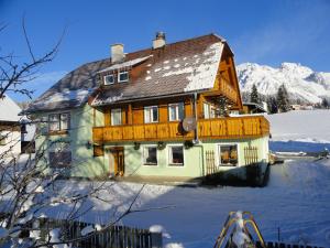 uma casa na neve com montanhas ao fundo em Jagerhäusl em Ramsau am Dachstein