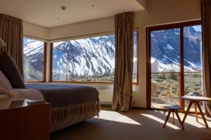 a bedroom with a large window with a mountain view at Lodge El Morado in Refugio Lo Valdés