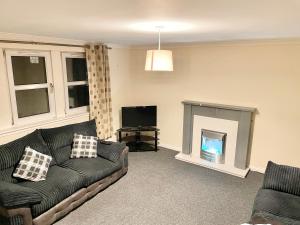 a living room with a couch and a fireplace at Modern 2 bed flat, private parking & sec entry in Gourock