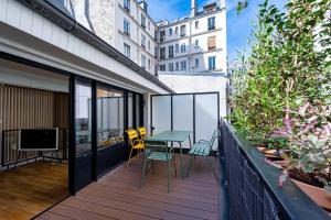 uma varanda com uma mesa e cadeiras e uma televisão em Magnifique appartement 2BR/4P - Marais/Bastille em Paris