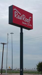a red and white sign on top of a pole at Red Roof Inn & Suites Midland in Midland