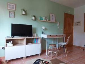 a living room with a television and a desk with a chair at APARTAMENTO PLAYA DE ESTORDE - Piscina y playa en el corazon da Costa da Morte in Cee